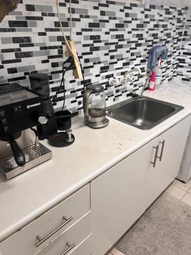 eine Küchentheke mit einer Spüle und einer Kaffeemaschine in der Unterkunft Leafy garden in Sydney