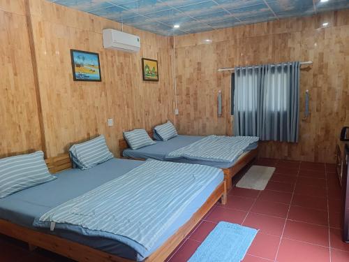 2 camas en una habitación con paredes de madera en The Sunrise Anh Tu, en Cam Ranh