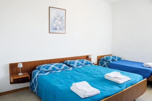 two beds in a room with blue sheets and towels at {Lux Kobler} - Luminoso Appartamento Fronte mare in Lido di Jesolo