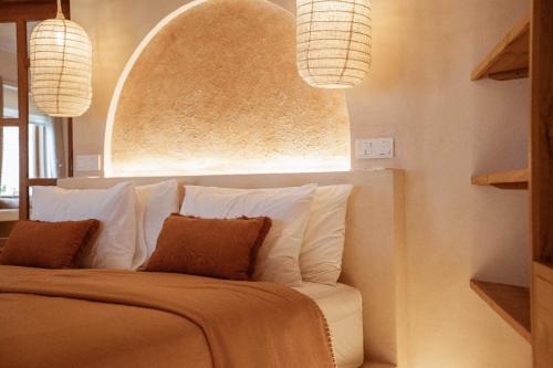 a bedroom with a bed with two pillows and two lights at Dune Seseh in Munggu