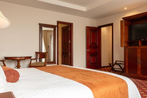 a bedroom with a large bed and a flat screen tv at Grand Victoria Boutique Hotel in Loja