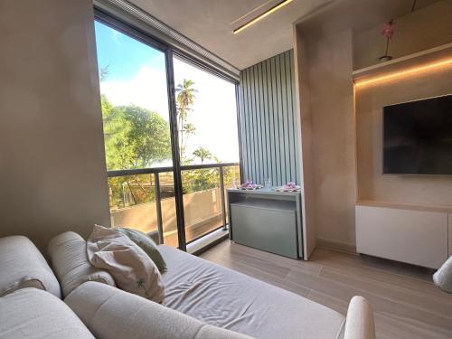 a living room with a couch and a large window at Flat beira mar de Cabo Branco em João Pessoa Setai YACHT in João Pessoa