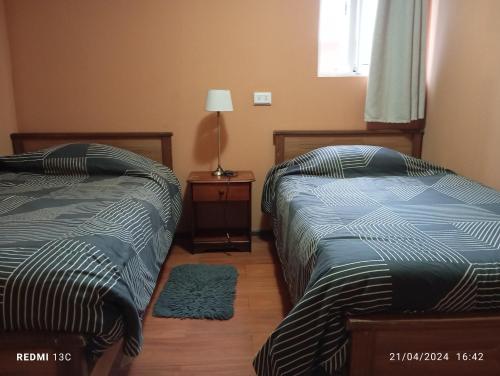 ein Schlafzimmer mit 2 Betten und einem Tisch mit einer Lampe in der Unterkunft Alojamiento jv CABAÑA in Nogales