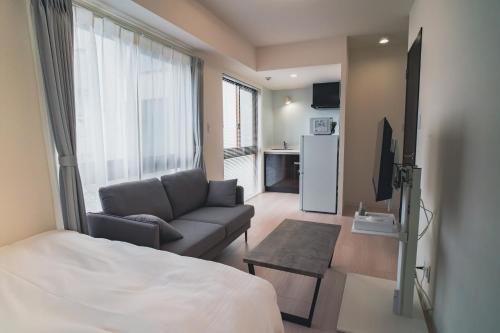 een woonkamer met een bed, een bank en een televisie bij Hotel Star Residence - 無人ホテル in Fukuoka