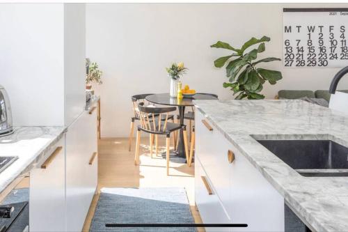 a kitchen with white cabinets and a table with a counter top at Freemans Bay Botanical Loft - Walk to Ponsonby & Waterfront in Auckland