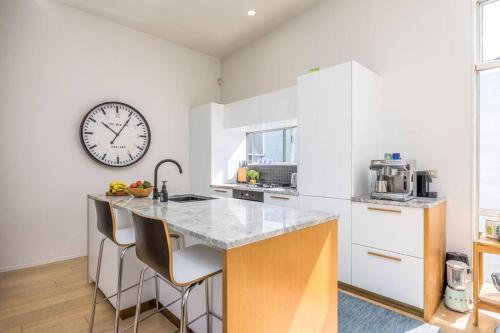 a kitchen with a counter with a clock on the wall at Freemans Bay Botanical Loft - Walk to Ponsonby & Waterfront in Auckland