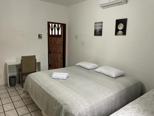 a bedroom with two beds and a desk and a window at Pousada aconchegante in Jequié