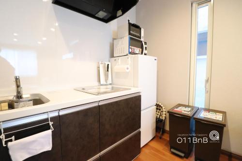 a kitchen with a white refrigerator and a sink at YI HOUSE MAX 8people 2BR 1 minute walk from tram station in Sapporo