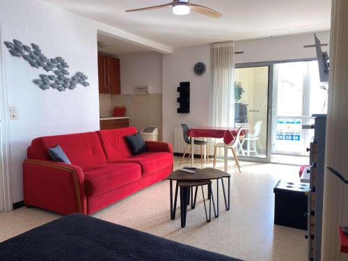 un salon avec un canapé rouge et une table dans l'établissement Studio proche des thermes avec loggia, cuisine équipée et électroménager complet - FR-1-553-255, à Balaruc-les-Bains