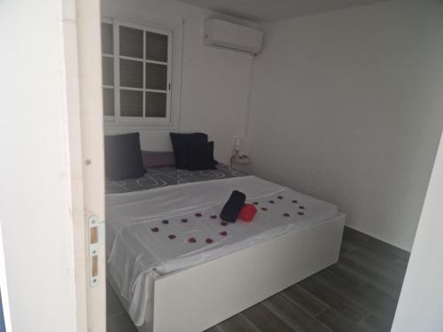 ein weißes Bett in einem weißen Zimmer mit Fenster in der Unterkunft Delices du Papillon in Petit-Bourg