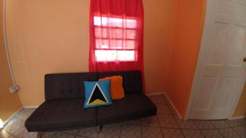 a couch with a pillow on it in front of a window at Southern Haven Beach House in Laborie