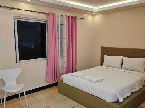 Schlafzimmer mit einem Bett und einem Fenster mit rosa Vorhängen in der Unterkunft Hotel Good Day in Angeles