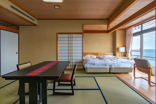 1 dormitorio con 1 cama, mesa y sillas en Atagawakan, en Higashiizu