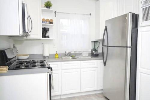 a kitchen with white cabinets and a stainless steel refrigerator at 2 Miles to Disneyland -FREE Parking! In Anaheim CA in Anaheim