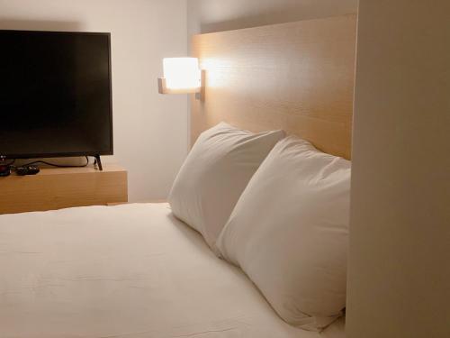 a pillow sitting on top of a bed with a television at Dahlbit stay in Incheon