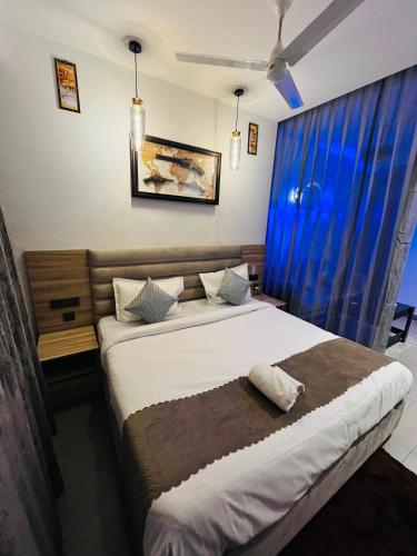 a bedroom with a large bed with blue curtains at The Luxury Lodge in Noida