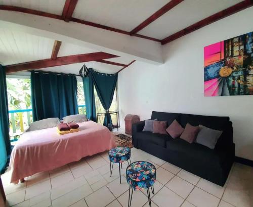 een slaapkamer met een bed en een bank bij Studio avec piscine partagee jardin clos et wifi a Sainte Anne a 1 km de la plage in Sainte-Anne