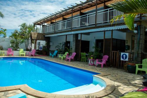 a pool in front of a house with pink and blue chairs at Hotel Ylang Ylang in Saint-Gilles-les-Bains