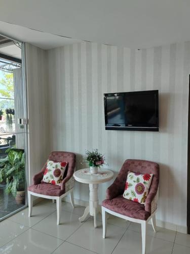 two chairs and a table with a tv on a wall at BG Business Hotel in Bukit Mertajam