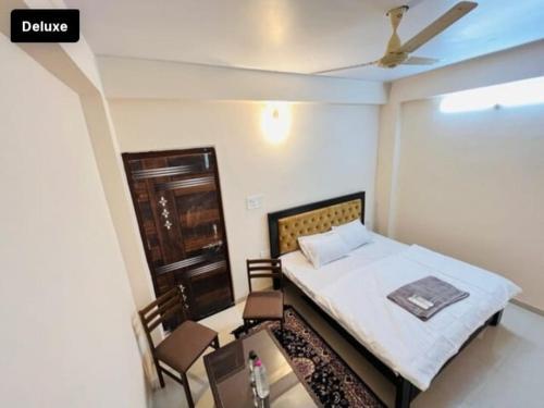 Hotel Green Villa في Rewa: غرفة نوم بسرير وطاولة وكراسي