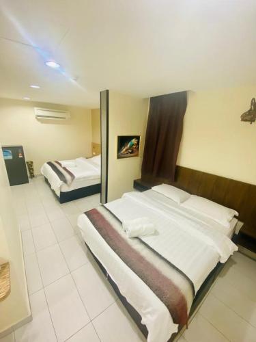 a hotel room with two beds and a mirror at BG Business Hotel in Bukit Mertajam