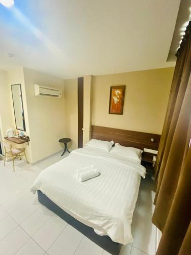 a bedroom with a large bed with white sheets at BG Business Hotel in Bukit Mertajam