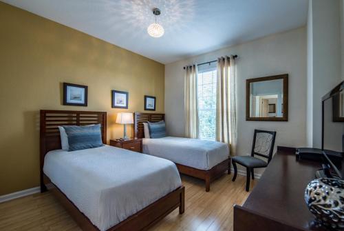 1 dormitorio con 2 camas, escritorio y espejo en Vista Cay 77 by Top Villas, en Orlando