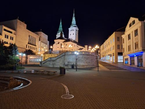 a city street at night with buildings and a clock tower at Vila Pohoda Javorníky s rozľahlým pozemkom in Makov