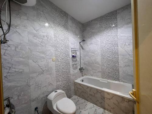 a bathroom with a toilet and a bath tub at بوتيك هاوس بدخول ذاتي وصالة أنيقة in Hail