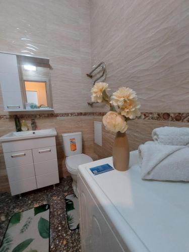 a bathroom with a toilet and a vase of flowers on a counter at Expo new life in Taldykolʼ