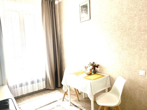 uma mesa e cadeiras num quarto com uma janela em Комфортные апартаменты на ЭКСО em Prigorodnyy