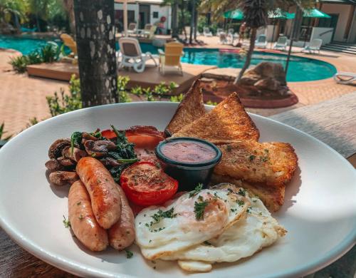 a plate of breakfast food with eggs sausage and toast at Ibis Darwin Airport Hotel in Darwin