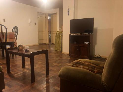 uma sala de estar com um sofá, uma mesa e uma televisão em Céntrico apartamento em La Paz