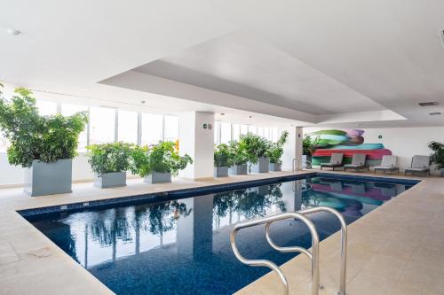 a swimming pool with potted plants in a building at Isolda Suites Vistas del Bosque in Mexico City