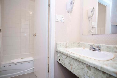 a bathroom with a sink and a shower and a phone at Sandman Inn McBride in McBride