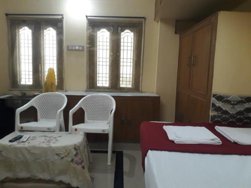 a room with two beds and a table and two chairs at Kodali Homestays in Bhadrāchalam