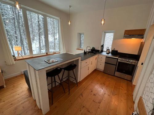 een keuken met een eiland met twee barkrukken bij Black Spruce - Yellow Door in Whitehorse