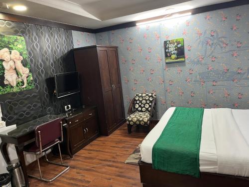 Schlafzimmer mit einem Bett, einem Schreibtisch und einem TV in der Unterkunft corporate stay in Neu-Delhi