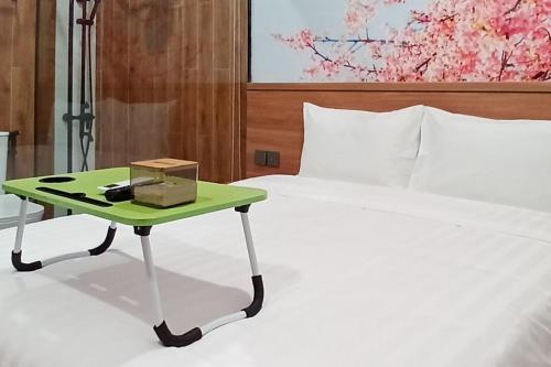 Urbanview Hotel R House Batuaji في Kubuk: سرير بطاولة خضراء بجانب سرير