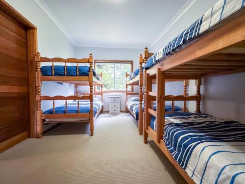 a room with three bunk beds in a house at Collingwood Beach Cottage - Belle Escapes Jervis Bay in Vincentia
