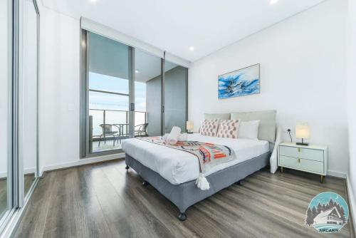 een slaapkamer met een bed en een groot raam bij Aircabin - Burwood - Modern Comfy - 2 Beds Apt in Sydney