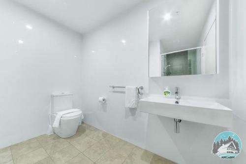 a white bathroom with a toilet and a sink at Aircabin - Burwood - Modern Comfy - 2 Beds Apt in Sydney