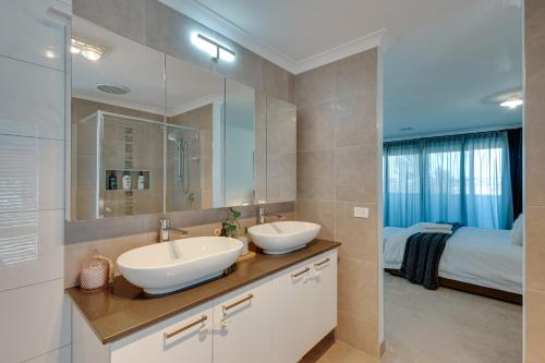 uma casa de banho com 2 lavatórios e uma cama em StayAU Cozy Holiday House 4BRM Big Group Tarneit em Tarneit