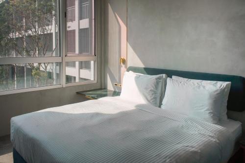 a bed with white sheets and pillows next to a window at PAPO'A Harbor Hotel in Kaohsiung