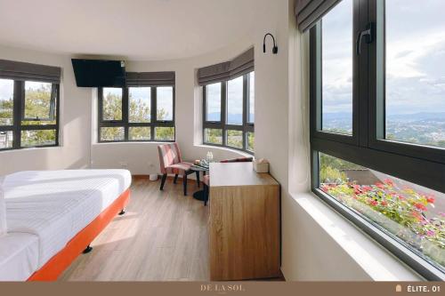 a bedroom with a bed and a desk with windows at De La Sol Villa Dalat in Da Lat