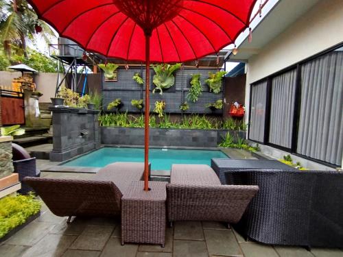 una sombrilla roja sobre 2 sillas y una piscina en Meliora bali villa, en Ubud