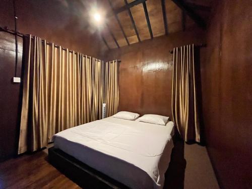 ein Schlafzimmer mit einem Bett in einem Zimmer mit Vorhängen in der Unterkunft Sembalun Kita Cottage in Sembalun Lawang