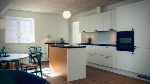 a kitchen with white cabinets and a counter top at Plesners Badehotel-Lejligheder in Skagen
