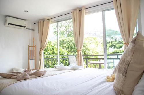 a bedroom with a large white bed with a large window at Kata Station Boutique Hotel in Kata Beach