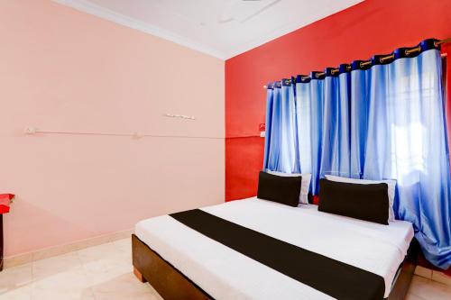 a bedroom with a bed with blue curtains at OYO Hotel Abhilasha in Bhilai